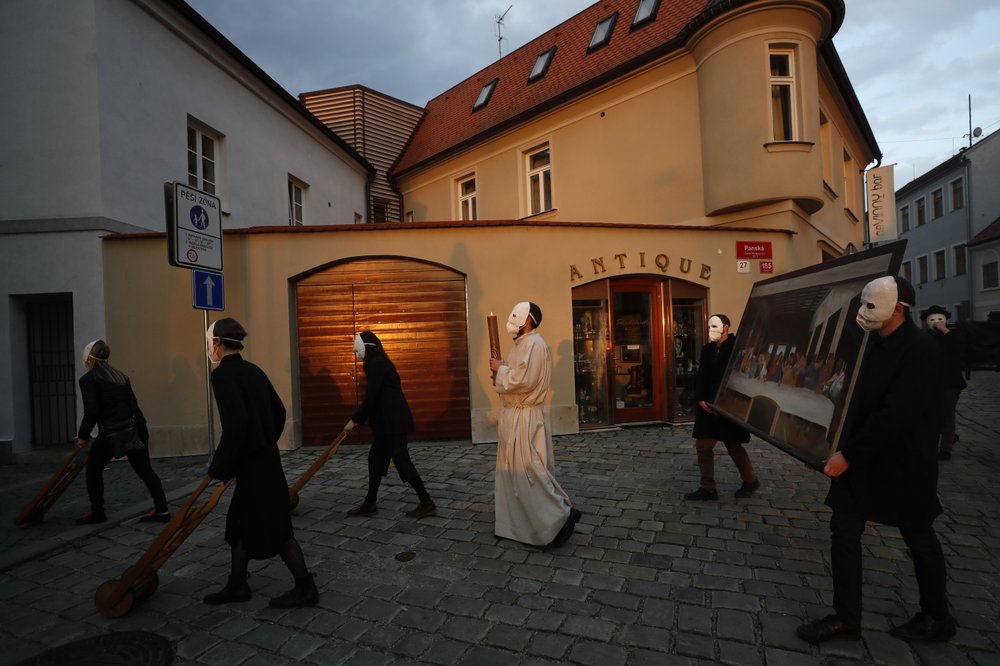 Participants dressed in black, wearing masks, beating drums and pushing small carts making a synchronized and loud sound take part in an Easter procession marching through the streets of Ceske Budejovice, Czech Republic, Thursday, April 1, 2021. The traditional event went ahead despite COVID-19 restrictions, although participants also wore medical face masks and observed social distancing as a precaution. (AP Photo/Petr David Josek)