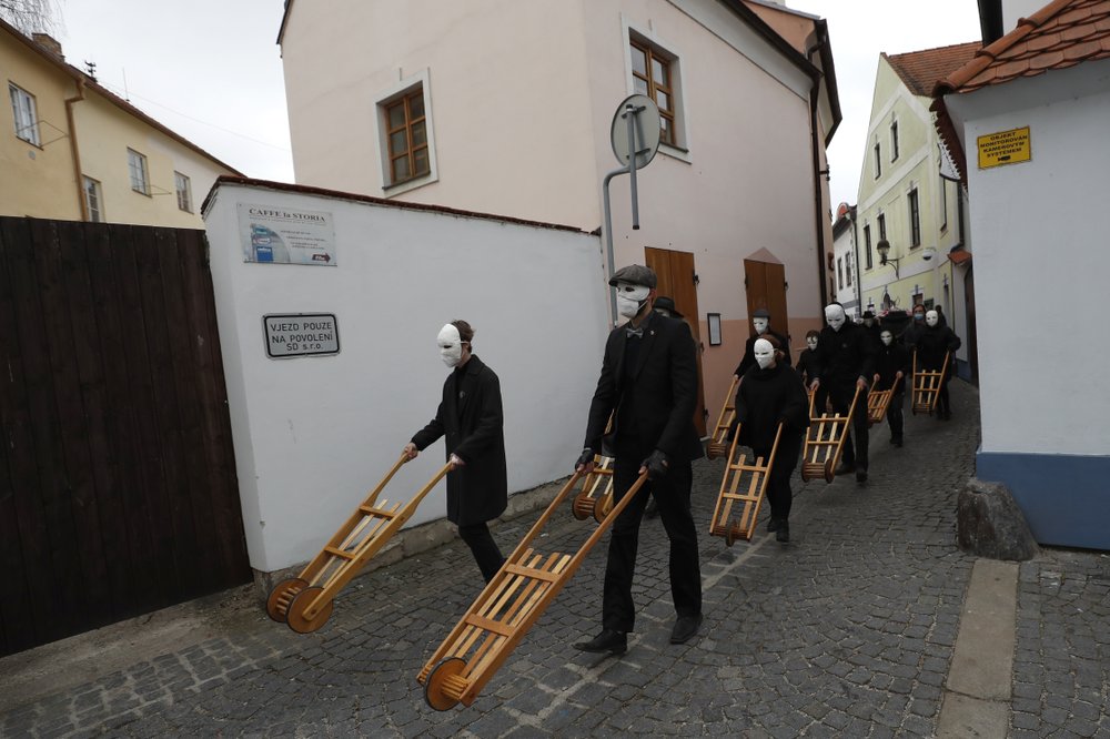 Participants dressed in black, wearing masks, beating drums and pushing small carts making a synchronized and loud sound take part in an Easter procession marching through the streets of Ceske Budejovice, Czech Republic, Friday, April 2, 2021. (AP Photo/Petr David Josek)