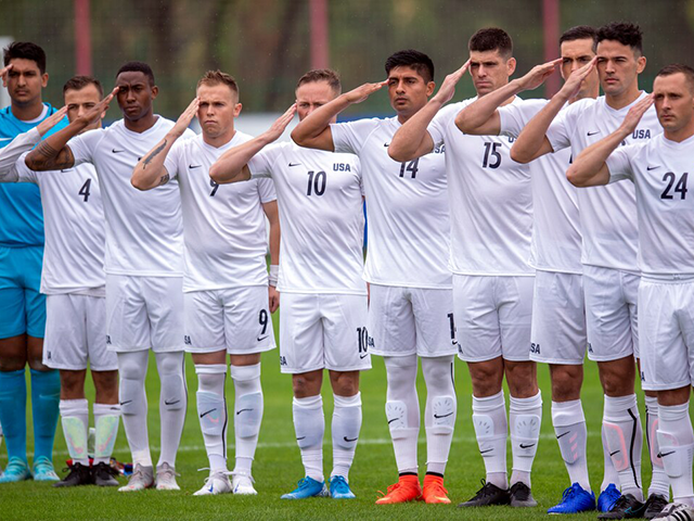 Armed Forces men’s soccer team members salute at the start of a preliminary round match