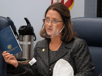 In this Jan. 27, 2021 file photo, Alaska state Sen. Lora Reinbold, an Eagle River Republican, holds a copy of the Alaska Constitution during a committee hearing in Juneau, Alaska. Alaska Airlines has banned the Alaska state senator for refusing to follow mask requirements. Last week Reinbold was recorded in …