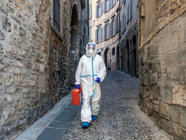 BERGAMO, ITALY - APRIL 3: (EDITORIAL USE ONLY) A member of the Italian Red Cross walks through an alley in the old town during his home visit to COVID-19 positive patients on April 3, 2020 in Bergamo, Italy. The number of new COVID-19 cases appears to be decreasing in Italy, …