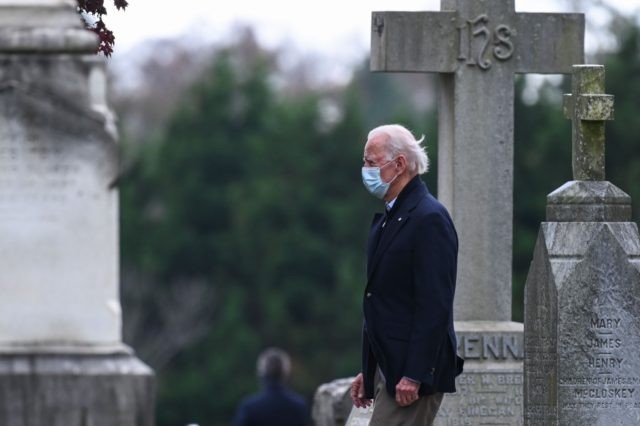 US President-elect Joe Biden walks past tombstones after leaving the St. Joseph on the Brandywine Catholic Church after attending Mass in Wilmington, Delaware on November 15, 2020. - President Donald Trump appeared accidentally to admit his election defeat in a tweet on Sunday morning -- before reversing course to claim …
