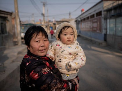A woman holds a baby on a street in Beijing on February 25, 2021. (Photo by NICOLAS ASFOURI / AFP) (Photo by NICOLAS ASFOURI/AFP via Getty Images)