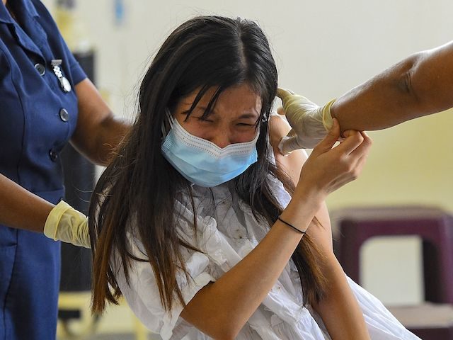 A health worker inoculates the Chinese-made Sinopharm vaccine to a Chinese national living in Sri Lanka, at the Colombo Port City project premises, in Colombo on April 6, 2021, after local health authorities cleared the use of the Chinese-made jab only for Chinese nationals resident in the island. (ISHARA S. …