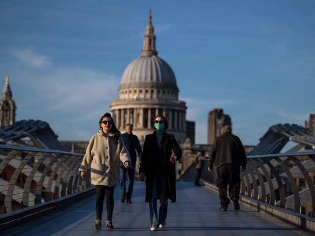 LONDON, ENGLAND - MARCH 16: A woman crosses the millennium bridge in front of St Pauls Cat