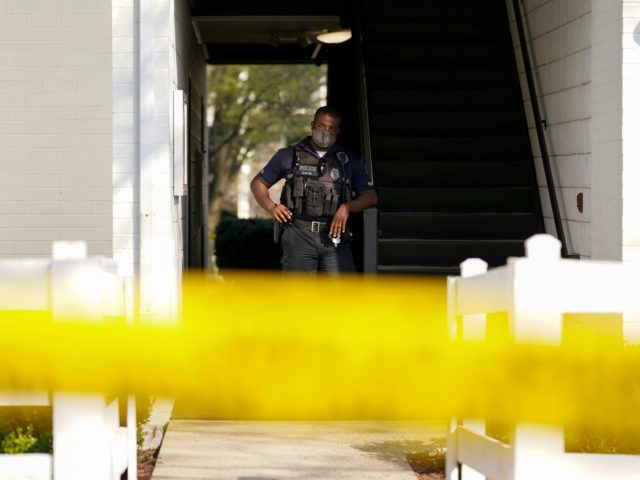 A police officer stands behind police tape outside the apartment of Navy Petty Ofc. 3rd Cl