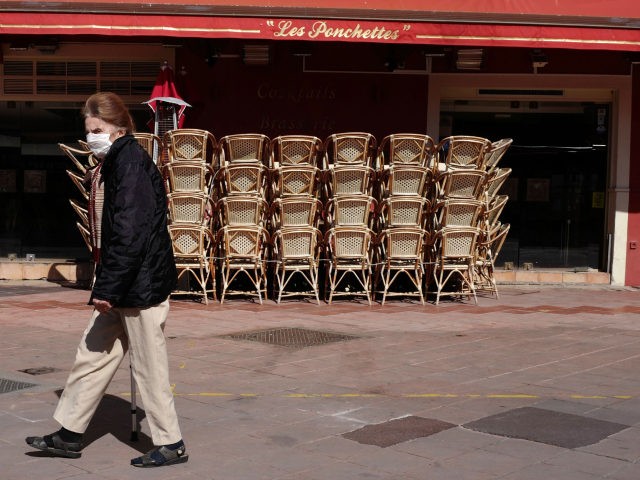 A woman wearing a face mask walks in front of restaurant closed due to the novel coronavir