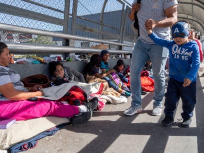 People walk past migrants camped out waiting to declare asylum on the Paso Del Norte Bridge on November 4, 2018 in El Paso, Texas. - Sending thousands of troops to the US-Mexico border to counter a migrant "invasion," questioning the validity of birthright citizenship, and spreading stories of scandalous murders …