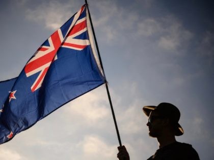 A man raises a New Zealand flag as he attends a vigil in memory of the twin mosque massacre victims in Christchurch on March 24, 2019. - New Zealand will hold a national remembrance service for victims of the Christchurch massacre on March 29, the government announced, as the country …