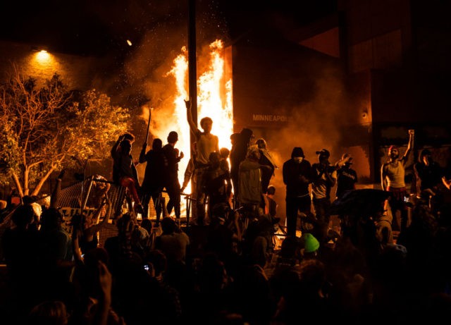 MINNEAPOLIS, MN - MAY 28: Protesters cheer as the Third Police Precinct burns behind them on May 28, 2020 in Minneapolis, Minnesota. As unrest continues after the death of George Floyd, police abandoned the precinct building, allowing protesters to set fire to it. (Photo by Stephen Maturen/Getty Images)