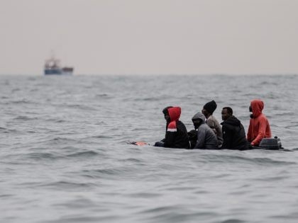 Migrants sit onboard a boat navigating in agitated waters between Sangatte and Cap Blanc-N