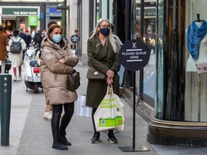 People queue outside shops wearing protective face masks as a precaution against the transmission of the novel coronavirus in Dublin on October 21, 2020 as Ireland prepares to enter a second national lockdown to stem the spread of the virus that causes Covid-19. - Millions of people in Ireland were …