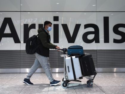 A passenger walks through the arrivals hall at Terminal 5, Heathrow Airport in west London