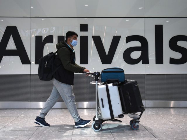 A passenger walks through the arrivals hall at Terminal 5, Heathrow Airport in west London on February 15, 2021. - The government from today will require all UK citizens and permanent residents returning from 33 countries on its so-called travel ban list to self-isolate in a government approved facility for …