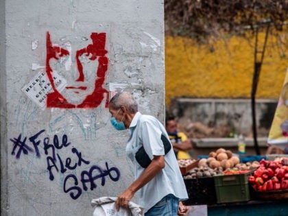 A man walks past a graffiti demanding Colombian businessman Alex Saab's freedom, in Caraca