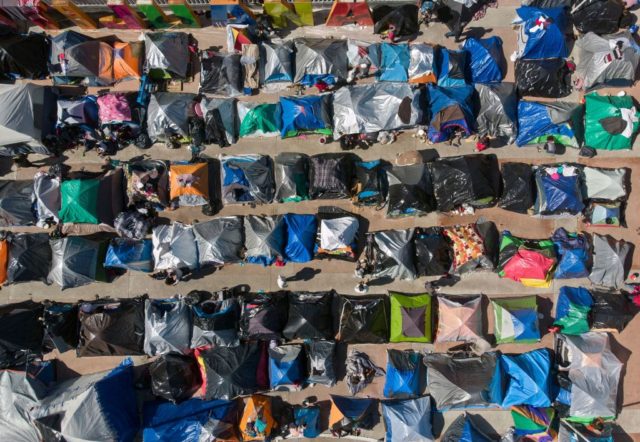 TOPSHOT - Aerial view of a migrants camp where asylum seekers wait for US authorities to allow them to start their migration process outside El Chaparral crossing port in Tijuana, Baja California state, Mexico on March 17, 2021. - President Biden's pledge of a more humane approach has sparked a …