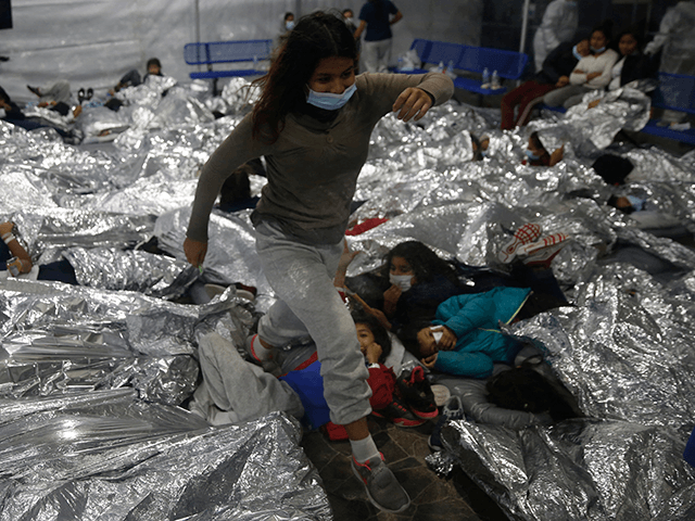 A young female minor walks over others as they lie inside a pod for females at the Donna Department of Homeland Security holding facility, the main detention center for unaccompanied children in the Rio Grande Valley run by the US Customs and Border Protection, (CBP), in Donna, Texas on March 30, 2021. - The minors are housed by the hundreds in eight pods that are about 3,200 square feet in size. Many of the pods had more than 500 children in them. The Biden administration on Tuesday for the first time allowed journalists inside its main detention facility at the border for migrant children, revealing a severely overcrowded tent structure where more than 4,000 kids and families were crammed into pods and the youngest kept in a large play pen with mats on the floor for sleeping. (Photo by Dario Lopez-Mills / POOL / AFP) (Photo by DARIO LOPEZ-MILLS/POOL/AFP via Getty Images)