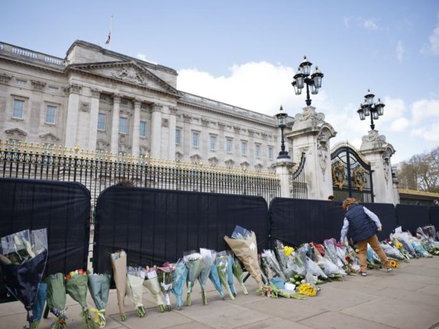 A well-wisher adds flowers to the tributes outside Buckingham Palace in central London, on