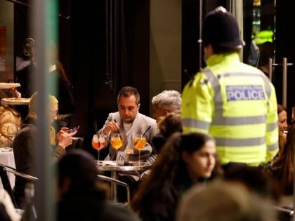 Police officers wearing protective face coverings to combat the spread of the coronavirus, speak with customers enjoying drinks at tables outside the pubs and bars in the Soho area of London, on April 12, 2021 as coronavirus restrictions are eased across the country in step two of the government's roadmap …