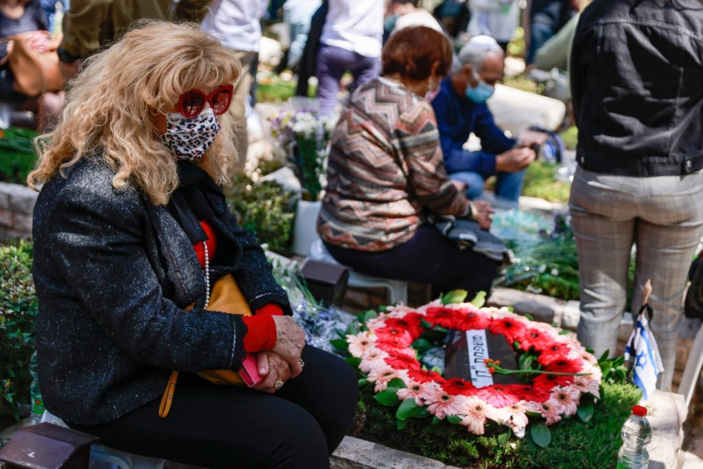 A mourner sits by the grave of a loved one at the Mount Herzel military cemetery in Jerusalem during Yom HaZikaron (Israel's Remembrance Day for fallen soldiers) on April 14, 2021. - Israel annually marks Yom HaZikaron to commemorate 23,928 fallen soldiers and fighters since 1860, just before the celebrations marking the Jewish State's 73rd anniversary, according to the Jewish calendar. (Photo by MENAHEM KAHANA / AFP) (Photo by MENAHEM KAHANA/AFP via Getty Images)
