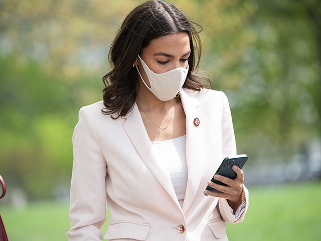 US Representative Alexandria Ocasio-Cortez, Democrat of New York, looks at her cellphone prior to a press conference about a postal banking pilot program outside the US Capitol in Washington, DC, April 15, 2021. (Photo by SAUL LOEB / AFP) (Photo by SAUL LOEB/AFP via Getty Images)