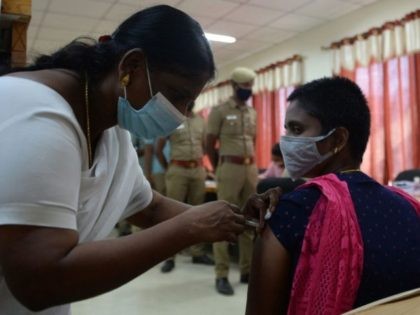 A medical worker inoculates a policewoman with a Covishield Covid-19 coronavirus vaccine a