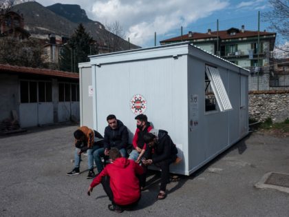 Kurdish migrants smoke cigarettes and wait at the Rifugio Fraternit Massi by Talita Onlus in Oulx, Susa Valley, Alps Region, north-western Italy on April 22, 2021. - A shelter run by an NGO founded by a priest in the Italian Alps has been helping migrants cross into France since 2018. …