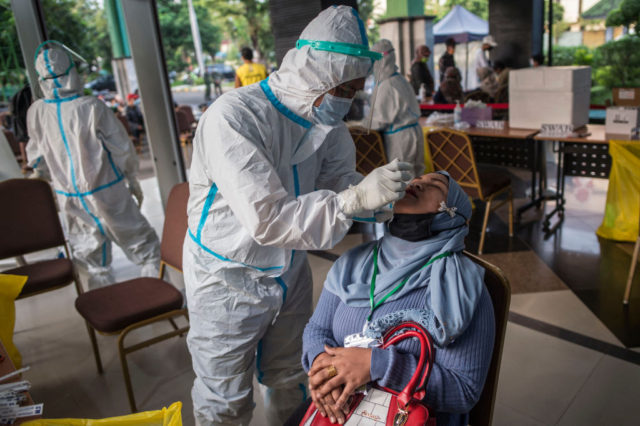 Health officials conduct Covid-19 screening on migrant workers who arrived back from Malaysia and Singapore in Surabaya on April 28, 2021, before they are quarantined. (Photo by Juni Kriswanto / AFP) (Photo by JUNI KRISWANTO/AFP via Getty Images)