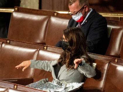 Representative Lauren Boebert (R-CO) spreads what appears to be a Mylar survival blanket o