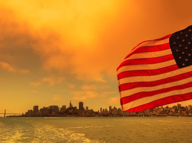 American flag with San Francisco Bay cityscape. Smoky orange sky for Californian fires in
