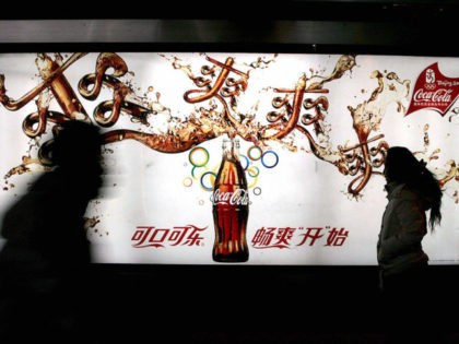 Passersby walk past a new Coca-cola advertisement billboard in Beijing, 09 December 2007. The Coca-Cola Company, the world's largest beverages producer, recently launched a research centre for traditional Chinese medicine in Beijing to develop beverages using Chinese herbal ingredients and formulas. AFP PHOTO (Photo credit should read AFP/AFP via Getty …