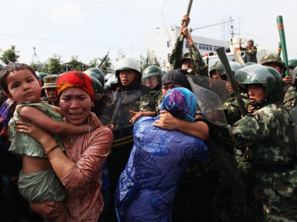 URUMQI, CHINA - JULY 07: Chinese policemen push Uighur women who are protesting at a stree