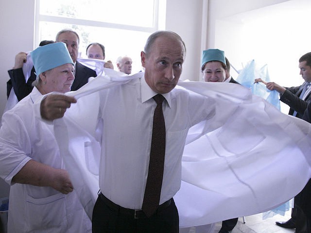 Russian Prime Minister Vladimir Putin puts on a white laboratory coat at a hospital during