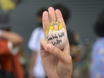 An anti-coup protester raises a decorated Easter egg along with the three-fingered symbol of resistance during a protest against the military coup on Easter Sunday, April 4, 2021, in Yangon, Myanmar. (AP Photo)