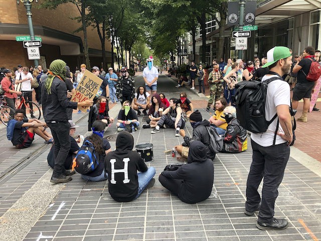 Anti-fascist counter-demonstrators sit down in Portland, Ore., Saturday, Aug. 17, 2019. Not all who gathered Saturday were with right-wing groups or antifa. Authorities closed bridges and streets to try to keep the rival groups apart. The city's mayor said the situation was "potentially dangerous and volatile," and President Donald Trump …