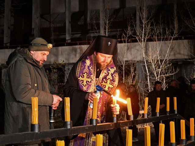 An orthodox priest lights candles on the central square of the ghost town of Pripyat near the Chernobyl Nuclear Power Plant early on April 26, 2021, to commemorate the 35th anniversary of the Chernobyl nuclear disaster. (Photo by Genya SAVILOV / AFP) (Photo by GENYA SAVILOV/AFP via Getty Images)