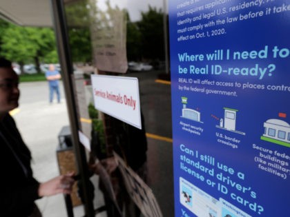 A customer opens the door of a Washington state Dept. of Licensing office in Lacey, Wash., Friday, June 22, 2018 next to a sign providing information about the requirements of Real ID. Some Washington licenses and identification cards will soon be marked with the words "federal limits apply" as the …