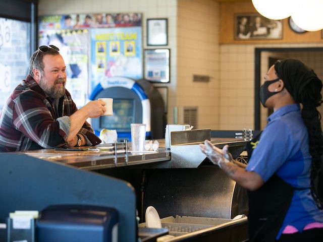 While an employee washes her hands, Ron Flexon sits at the counter for dine-in service at