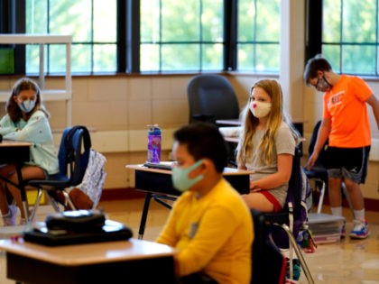 Students in fifth grade wear masks as they wait for their teacher in the classroom at Oak