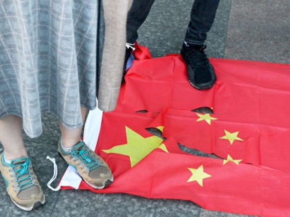 People stand on a torn Chinese national flag during a march in support of Save12, the campaign to save twelve Hong Kong pro-democracy activists, in central Taipei on October 25, 2020. (Chris Stowers/AFP via Getty Images)