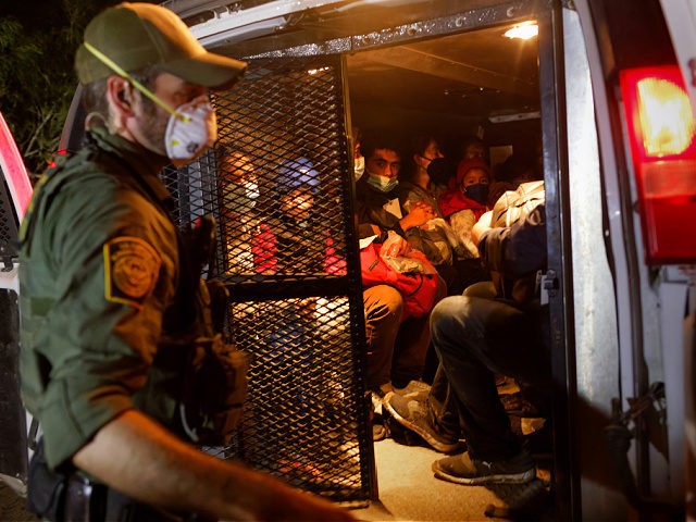 ROMA, TEXAS - APRIL 27: A U.S. Border Patrol agent loads immigrants into a transport van after they crossed the Rio Grande from Mexico on April 27, 2021 in Roma, Texas. A surge of mostly Central American immigrants crossing into the United States, including record numbers of children, has challenged …