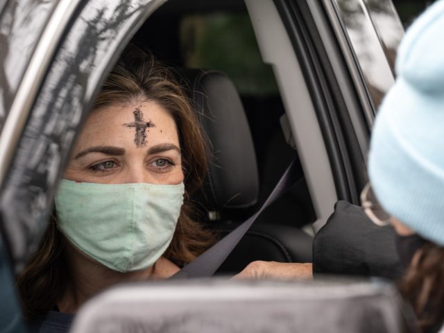 NEW ORLEANS, LA - FEBRUARY 17: A clergy member from Munholland United Methodist Church spreads ashes on the forehead of a congregant in the drive-thru Ash Wednesday prayer and imposition of ashes on February 17, 2021 in New Orleans, Louisiana. Ash Wednesday marks the start of the Lenten period leading …