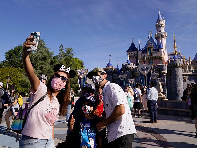 A family takes a photo in front of Sleeping Beauty's Castle at Disneyland in Anaheim,