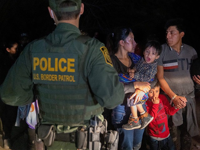 ROMA, TEXAS - APRIL 14: Immigrants wait for a U.S. Border Patrol agent to lead them up fro