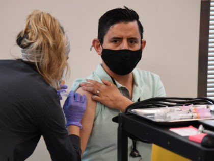 Concentra registered nurse Deysi Fleix (L) administers a Moderna COVID-19 vaccination to Amazon employee Juan Nunez at an Amazon fulfillment center on March 31, 2021 in North Las Vegas, Nevada. The company is offering employees vaccinations at its facility for eight days. (Photo by Ethan Miller/Getty Images)
