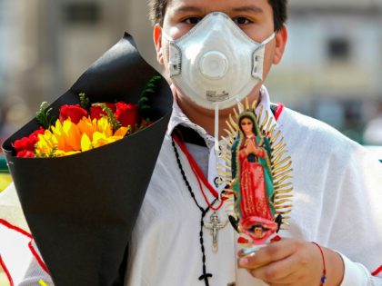 A Catholic faithful wears a face mask as he holds flowers outside the temple where the ima
