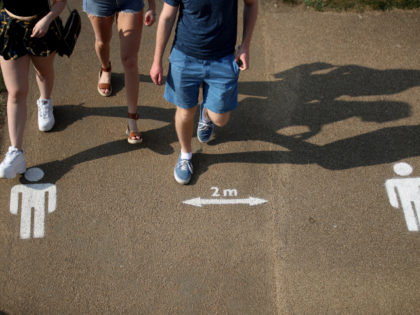 LONDON, ENGLAND - APRIL 11: People walk past the social distancing markings on the ground at Queen Elizabeth Olympic Park on April 11, 2020 in London, England. Public Easter events have been cancelled across the country, with the government urging the public to respect lockdown measures by celebrating the holiday …