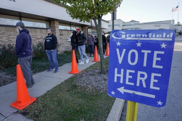 In this Nov. 3, 2020, file photo people line up to vote outside the Greenfield Community Center on Election Day in Greenfield, Wis. The Wisconsin Supreme Court sided with Democrats on Friday, April 9, 2020, and ruled that the state elections commission should not remove from the rolls voters flagged …