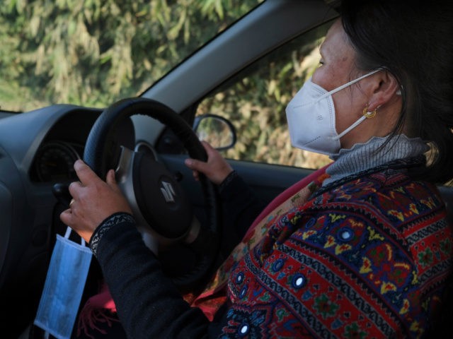 An extra face mask hangs by the steering wheel of nurse Shimray Wungreichon, 43, as she dr