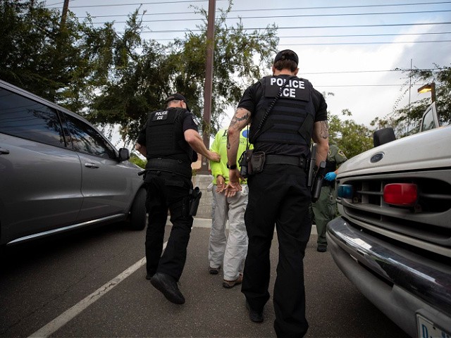 In this July 8, 2019, photo, a U.S. Immigration and Customs Enforcement (ICE) officers escort a man in handcuffs during an operation in Escondido, Calif. The carefully orchestrated arrest last week in this San Diego suburb illustrates how President Donald Trump's pledge to start deporting millions of people in the country illegally is virtually impossible with ICE's budget and its method of picking people up. (AP Photo/Gregory Bull)